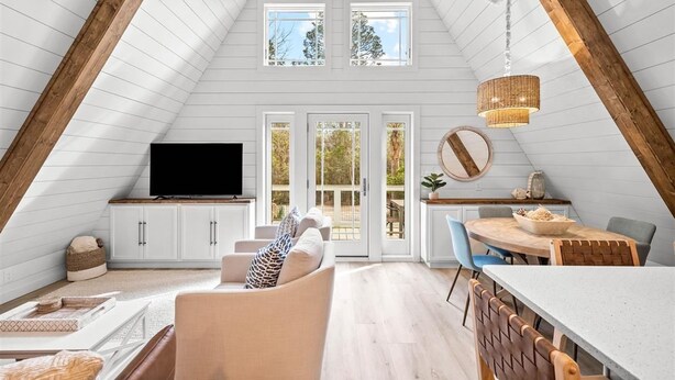 A loft-style room with a sloped ceiling, built-in TV, dining area, and large windows. - A-Frame of Mind - Stylish Santa Rosa Beach Retreat | Walk to Beach (Santa Rosa Beach)