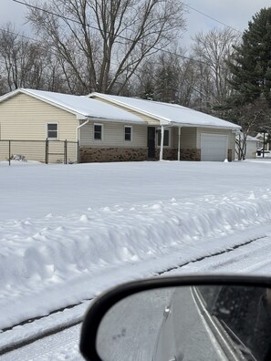 A residential area with two single-story houses, each with a garage, surrounded by snow-covered ground.