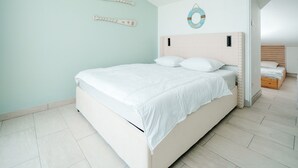 A bedroom with a bed, a headboard, a wall decoration, and a door leading to another room. - Light Filled Property Near Sea (Agde)