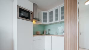 A compact kitchen with white cabinets, a microwave, a toaster, and a coffee maker. - Light Filled Property Near Sea (Agde)