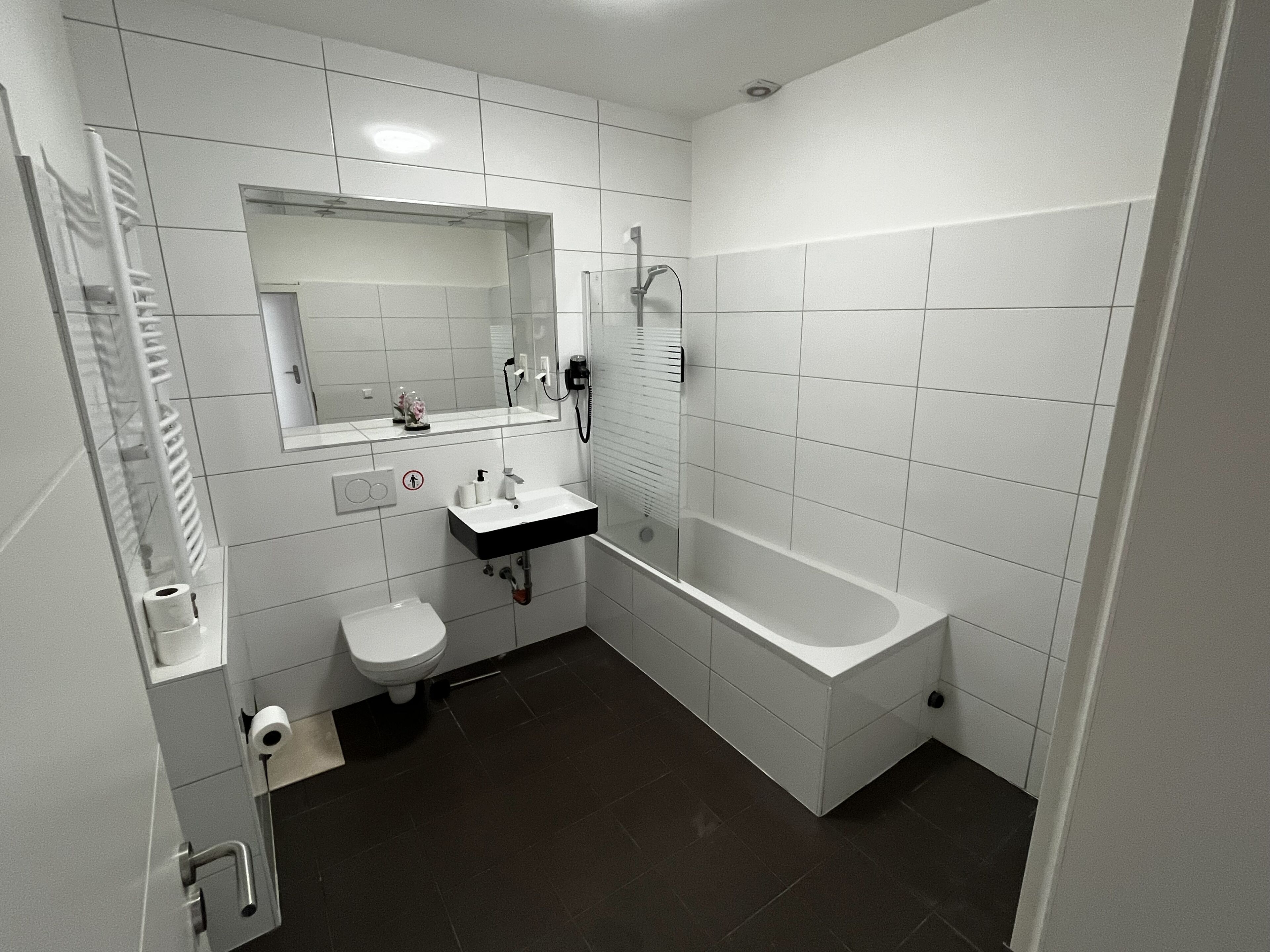 Ein modernes Badezimmer mit Toilette, Waschbecken, Spiegel und Badewanne.