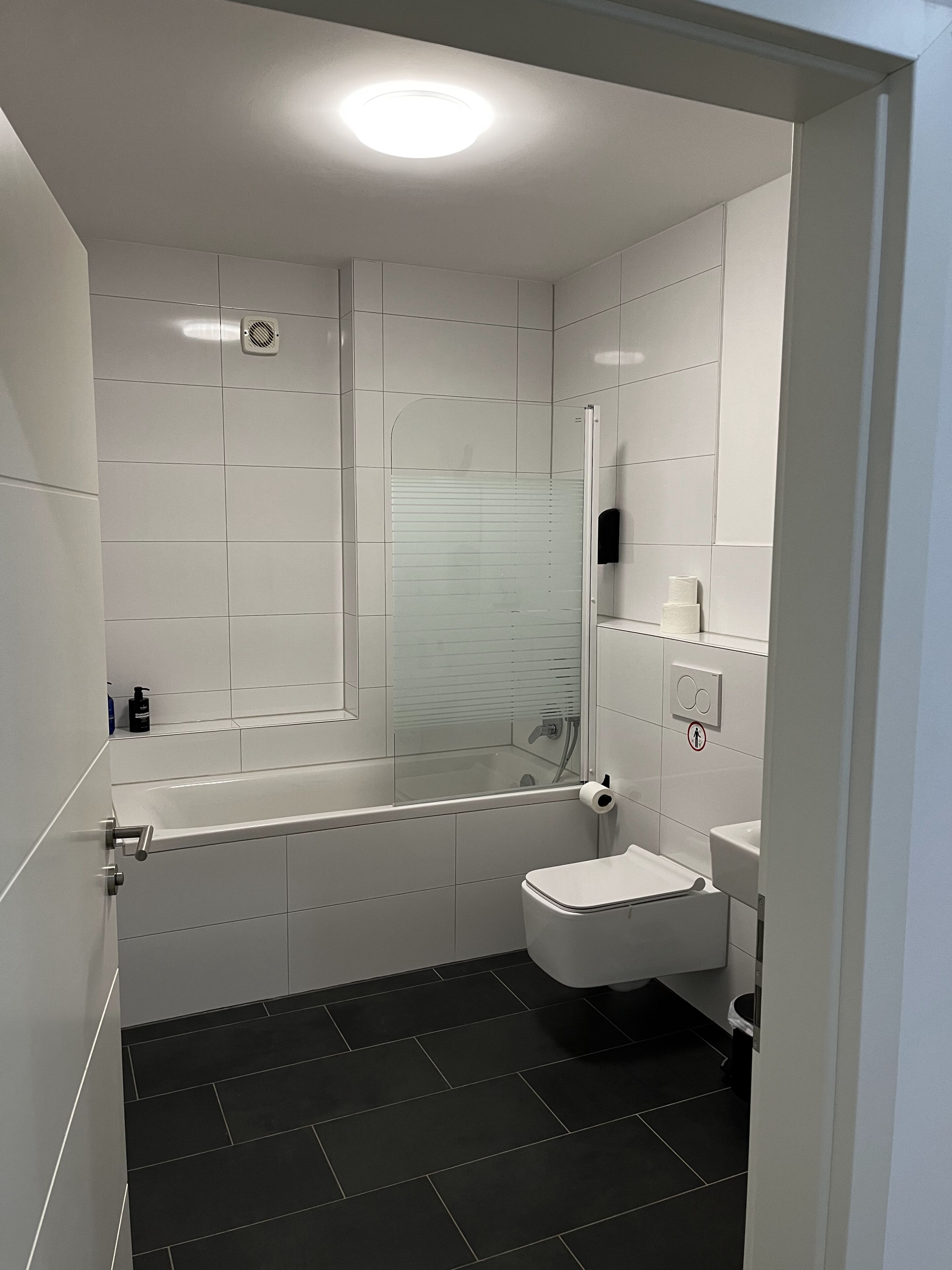 A modern bathroom with a bathtub, toilet, and sink.