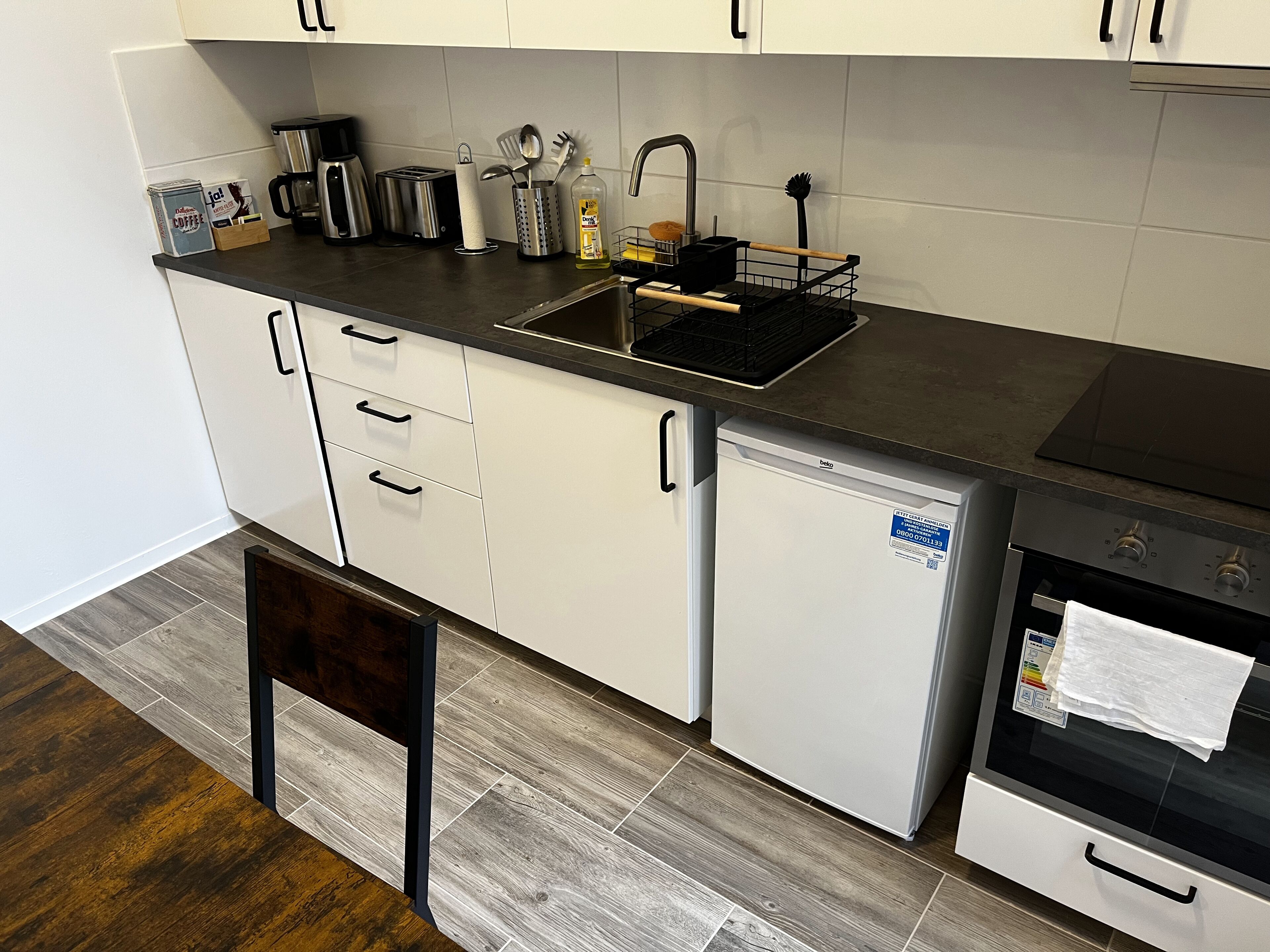 Eine kleine Küche mit Spüle, Toaster, Kaffeemaschine und kleinem Kühlschrank.