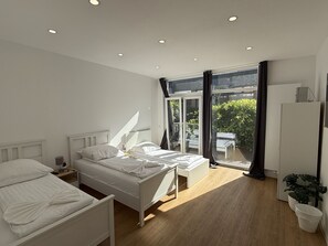 A modern bedroom with two beds, a large sliding glass door to a balcony, and a white wardrobe. - CityStay Bergisch Gladbach (Bergisch Gladbach)