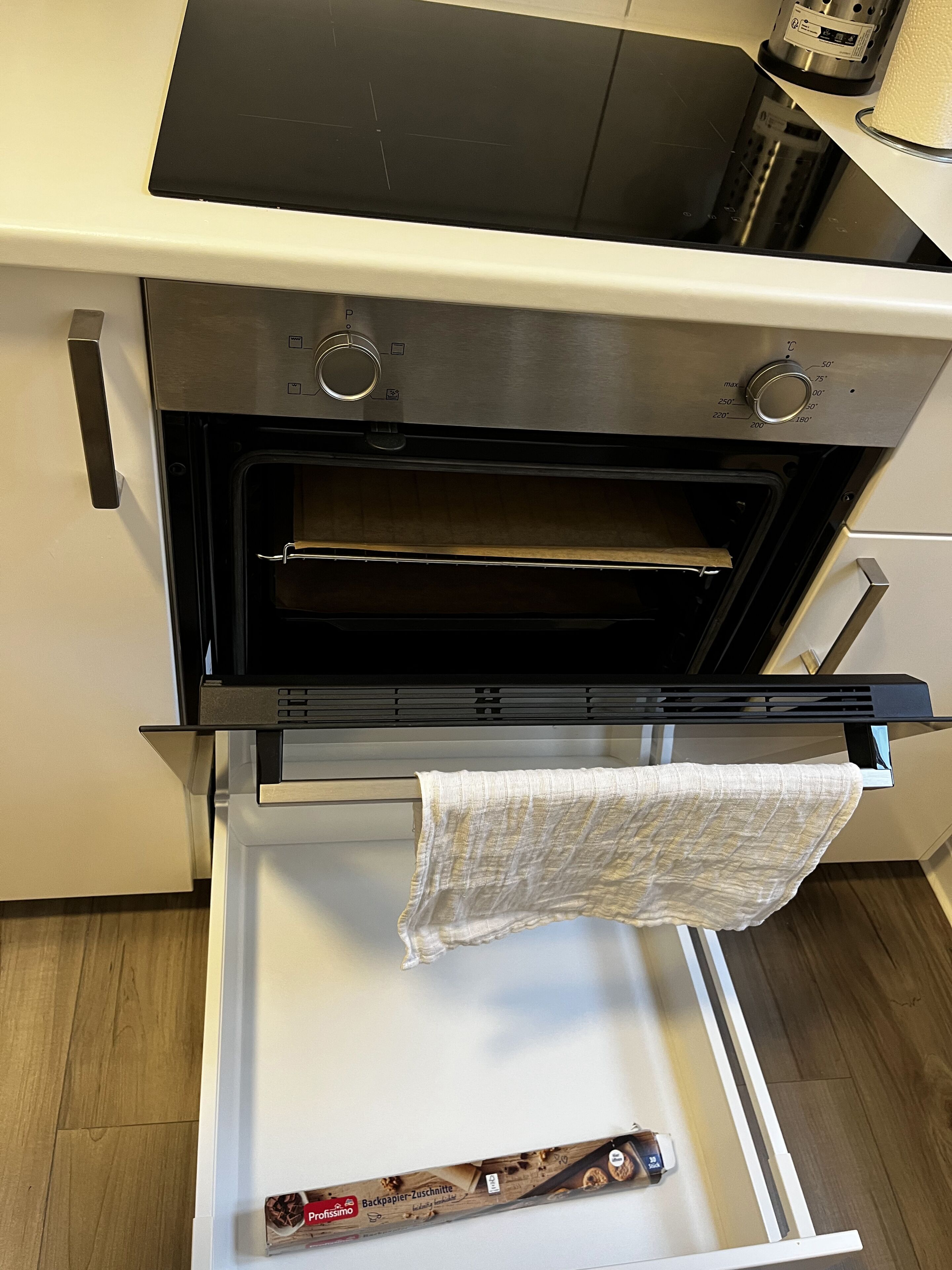 An oven with a temperature dial, a control panel, and a wooden rack inside.