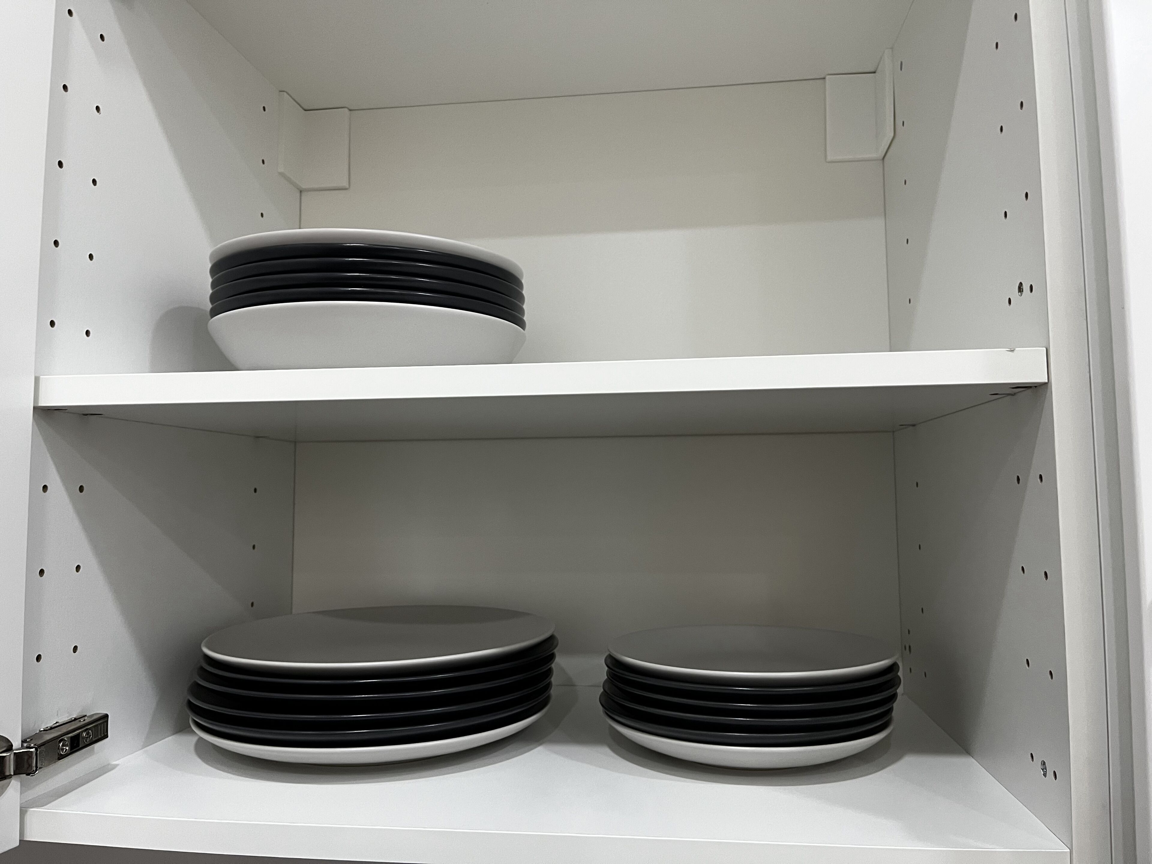 A white shelf unit with two rows of stacked plates.