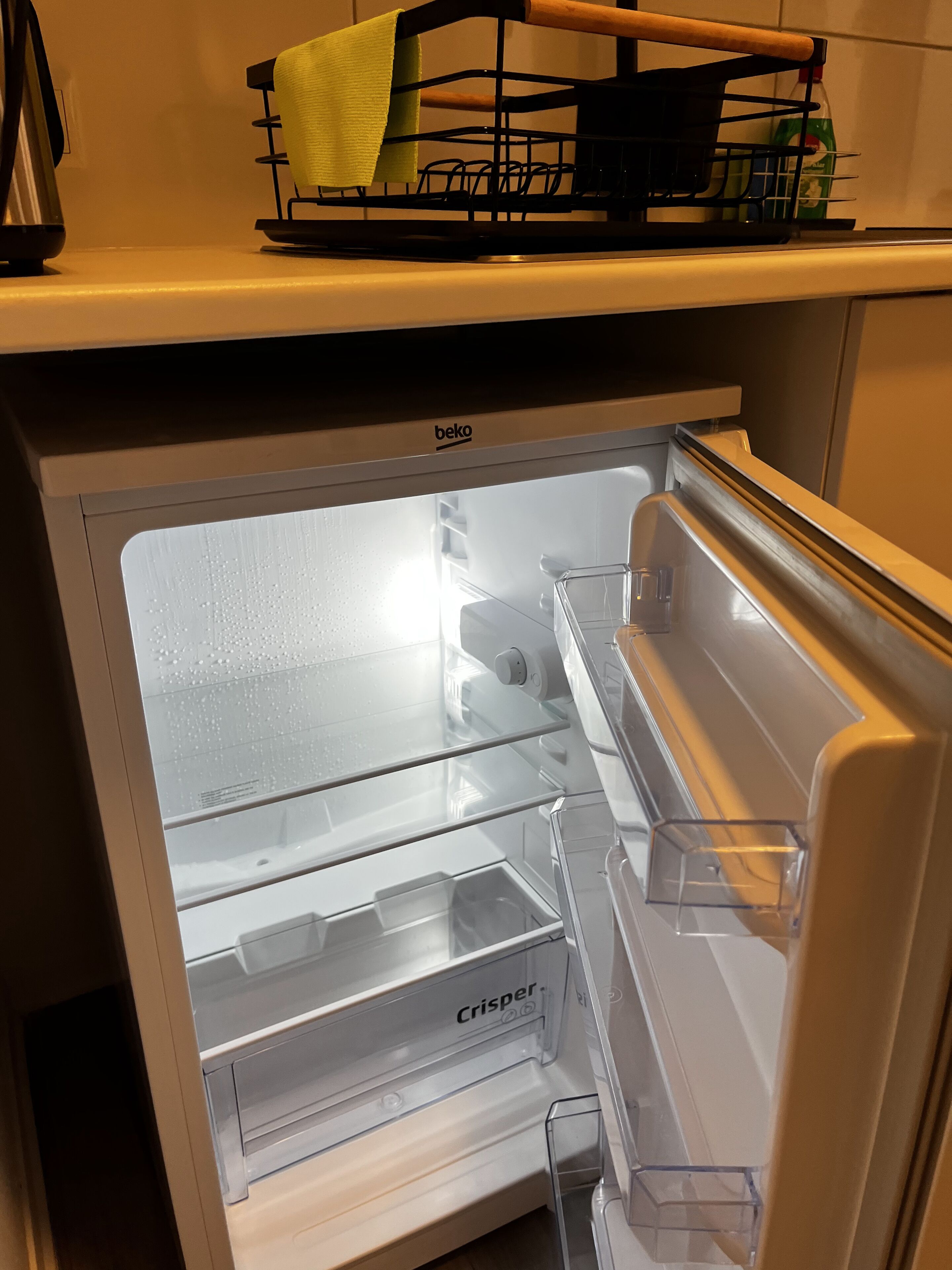 Ein Kühlschrank mit Glastür, Wasserspender und einem darüber liegenden Regal.