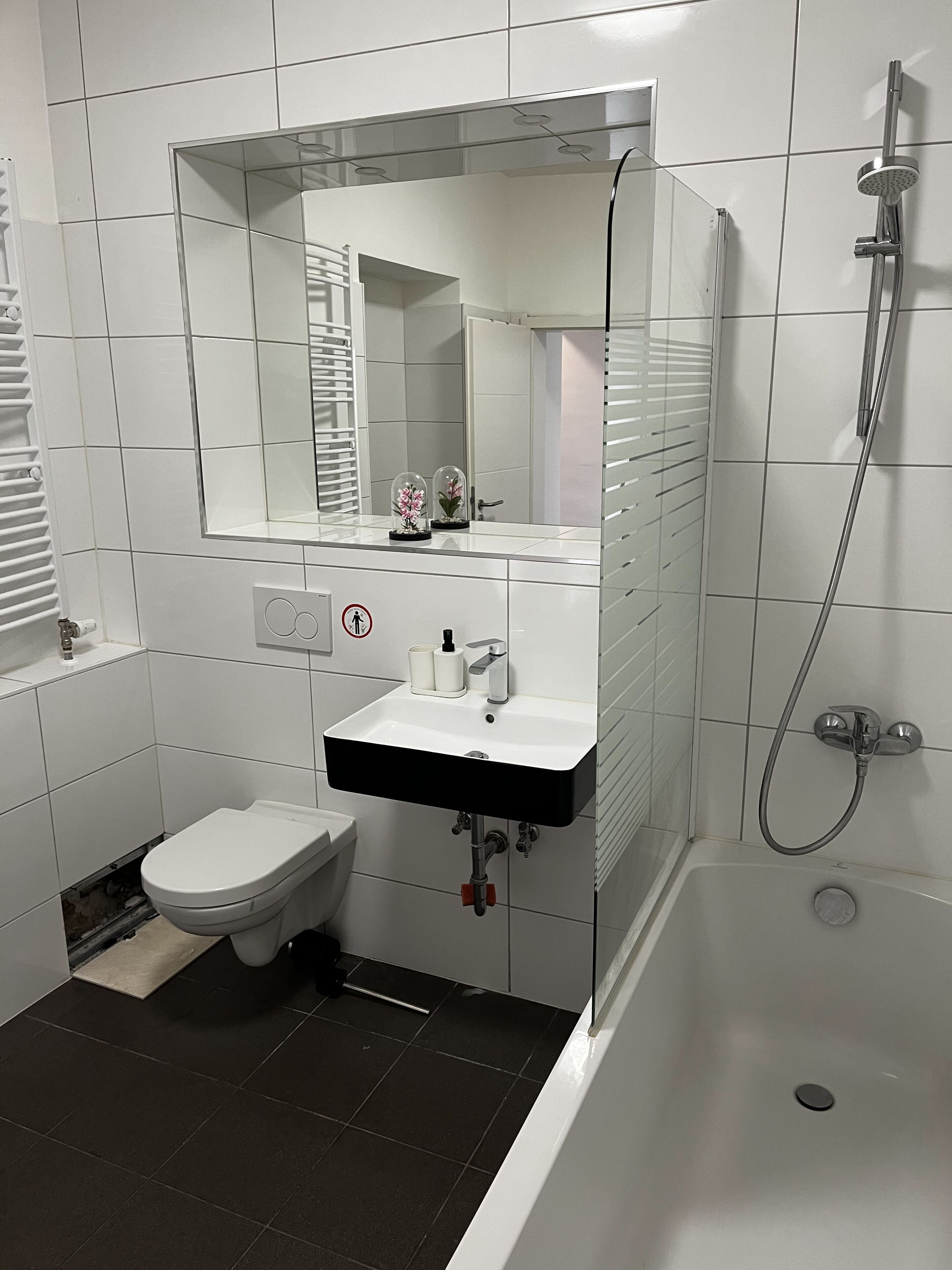 Un baño moderno con un lavabo blanco, inodoro, ducha y espejo sobre el lavabo.