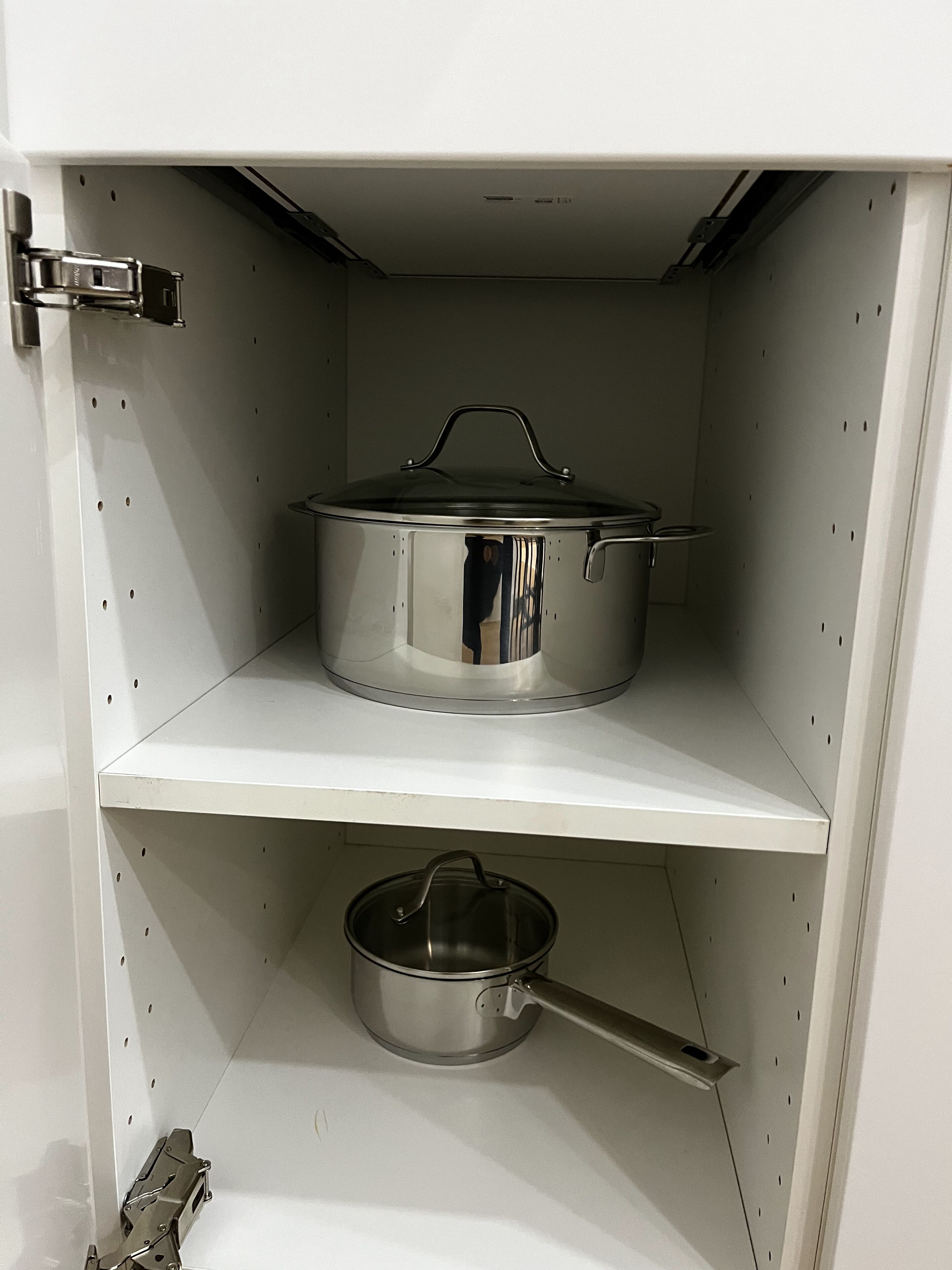 Una cocina con una olla de acero inoxidable en el estante superior y una olla más pequeña en el estante inferior.