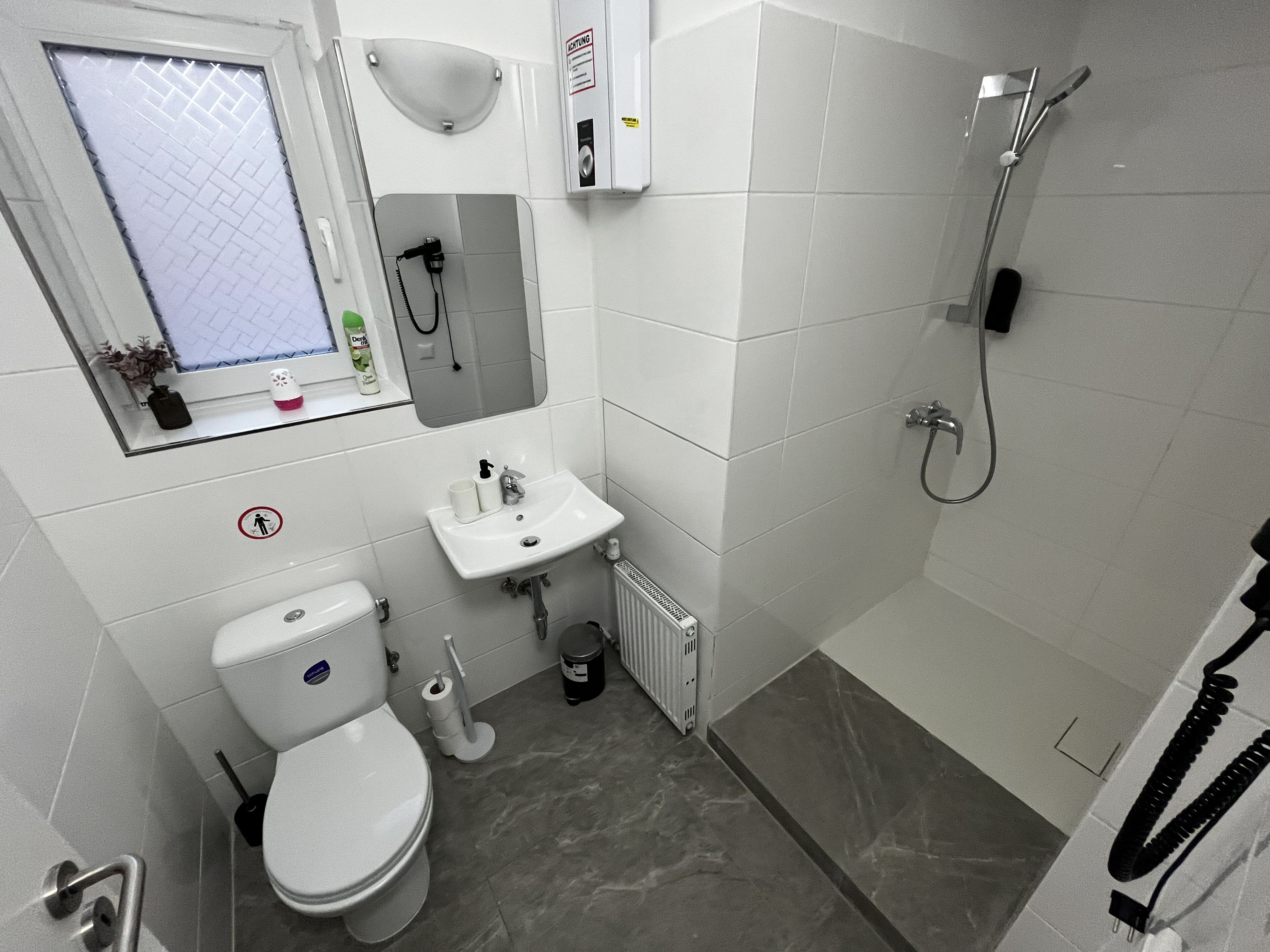 A compact bathroom with a toilet, sink, and shower.