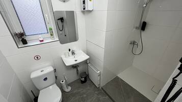 A compact bathroom with a toilet, sink, and shower.