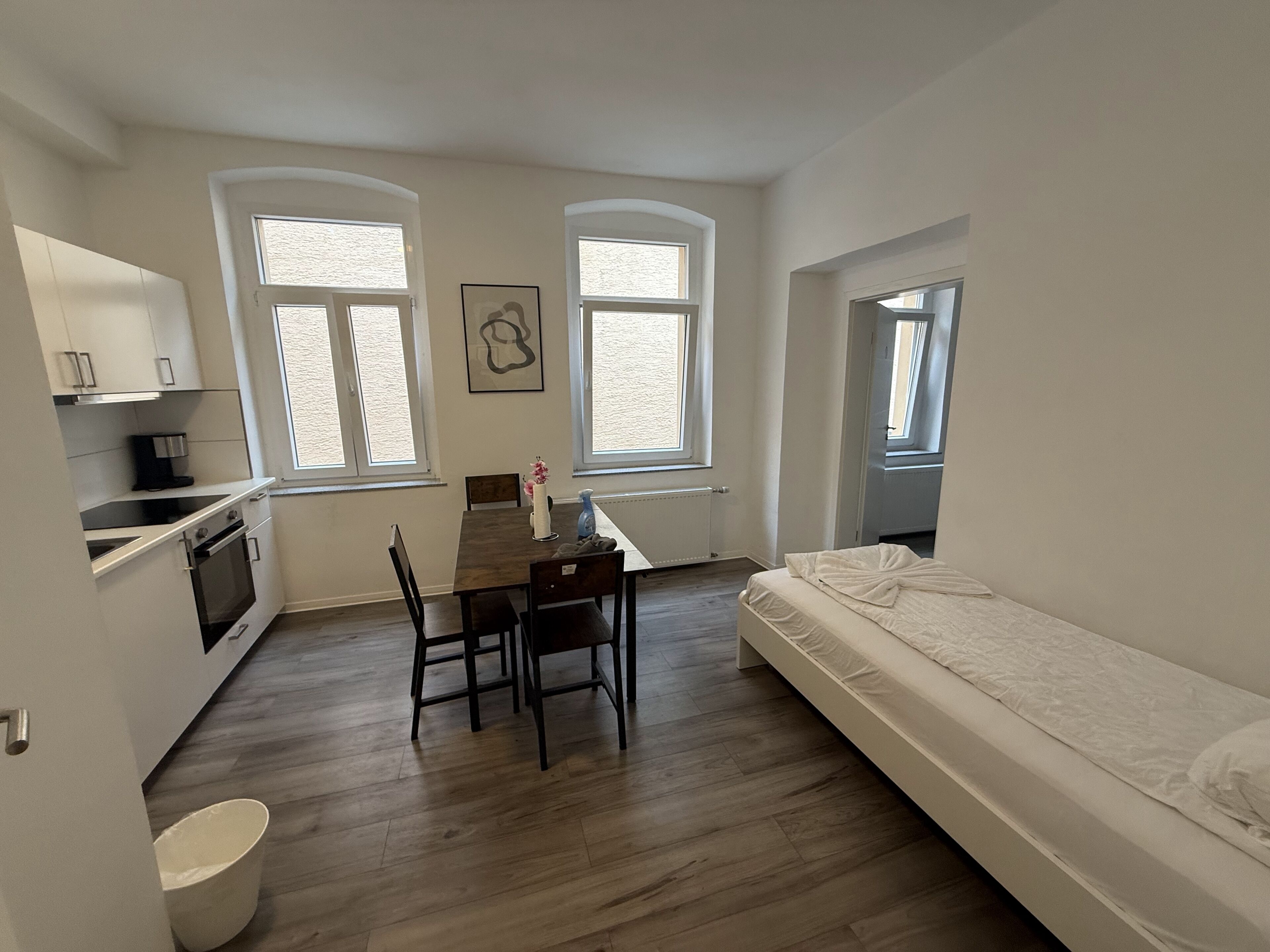 Une pièce compacte comprenant un coin cuisine, une table à manger et un lit.