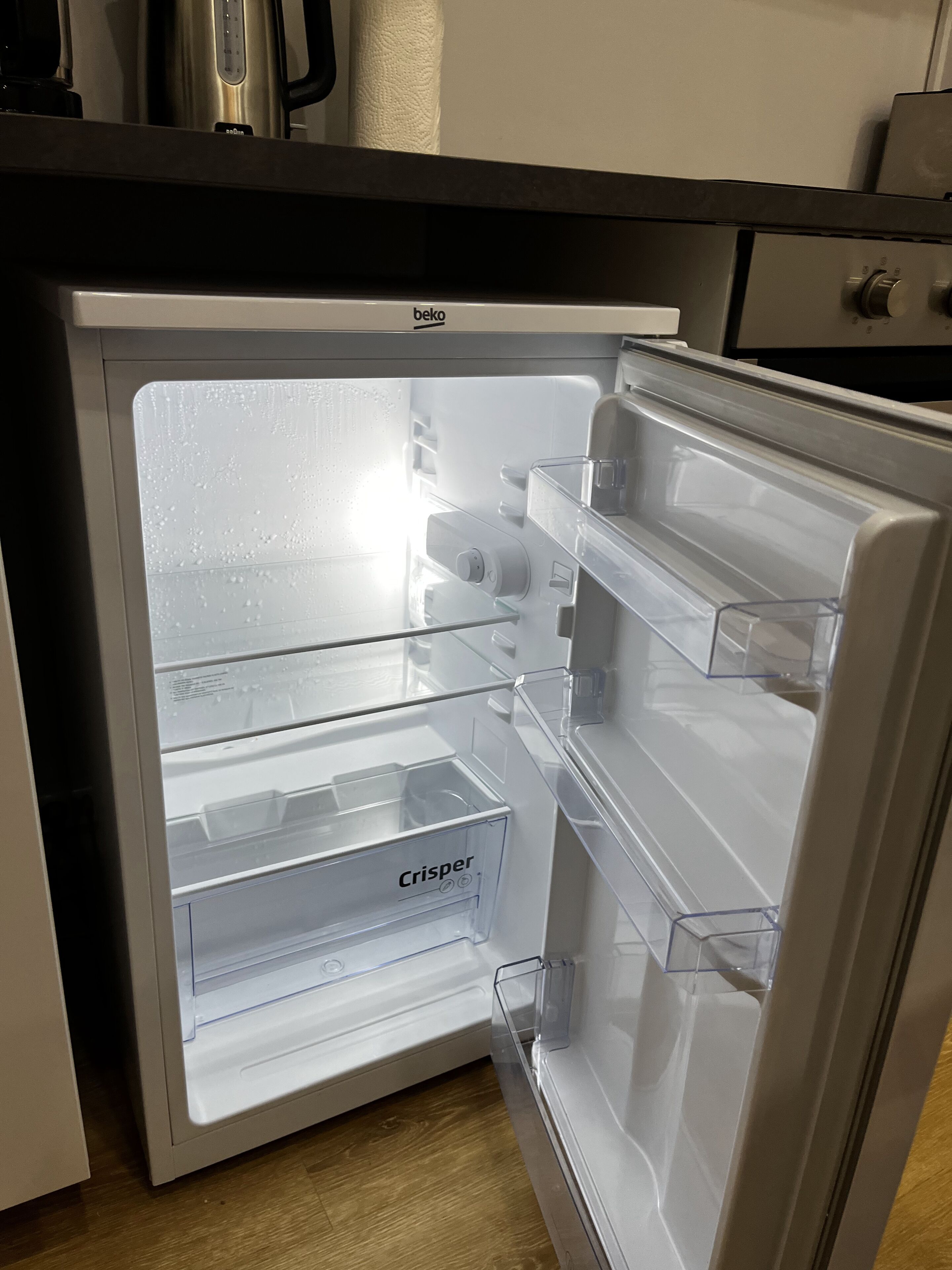 A refrigerator with multiple compartments, including a freezer and a crisp drawer, in a kitchen setting.