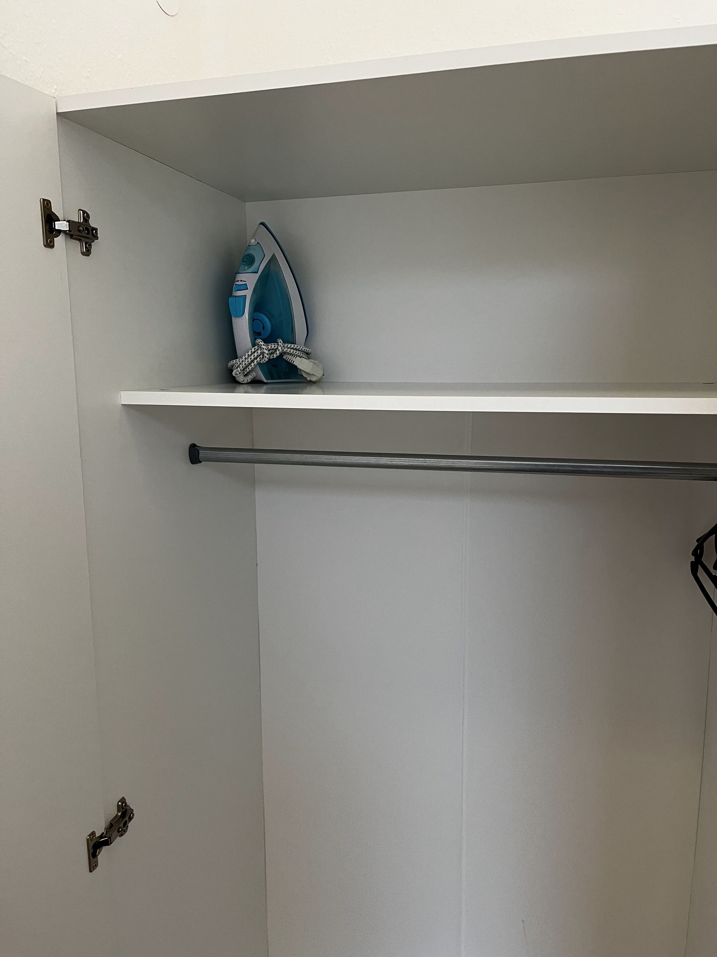 Une salle de bain avec une porte blanche, un porte-serviettes et un fer à repasser posé sur une étagère.