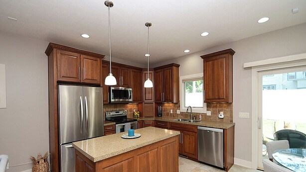 A modern kitchen with wooden cabinets, stainless steel appliances, and a central island. - 4 miles to " The Chuck" for CWS, 3 bed each with private bath, super clean! (Omaha)