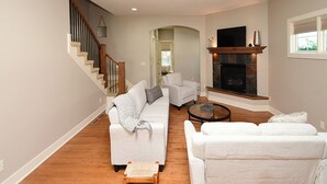 A spacious living room with a staircase, a fireplace, and a TV. - 4 miles to " The Chuck" for CWS, 3 bed each with private bath, super clean! (Omaha)