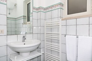 Een badkamer met een witte wastafel, spiegel en handdoekrek.