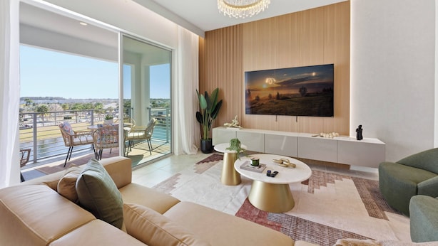 Ein modernes Wohnzimmer mit großem Fernseher, einem Balkon mit Sitzmöbeln und Blick auf die Stadt.