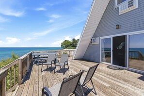 A wooden deck with chairs and a table overlooking the ocean.