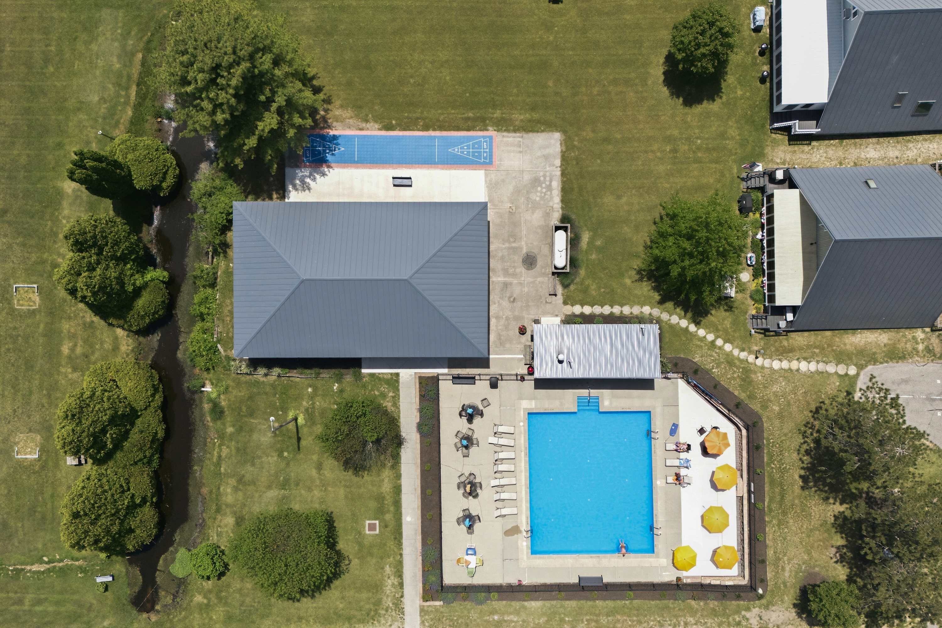 Vue aérienne d’une propriété dotée d’une piscine, d’un espace de détente extérieur et d’un parking.