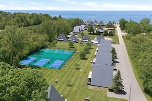 An aerial view of a residential area with houses, a tennis court, and a road.