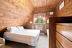 Ein Schlafzimmer mit einem Bett, einer Kommode, einem Fenster mit Vorhängen und einer wandmontierten Klimaanlage.