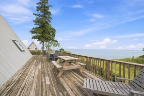 Eine Holzterrasse mit Picknicktisch und -stühlen mit Blick auf ein Gewässer.