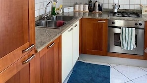 A kitchen with wooden cabinets, a stainless steel stove, and a tiled backsplash. - App. Accanto ai Mercatini di Natale (Trento)