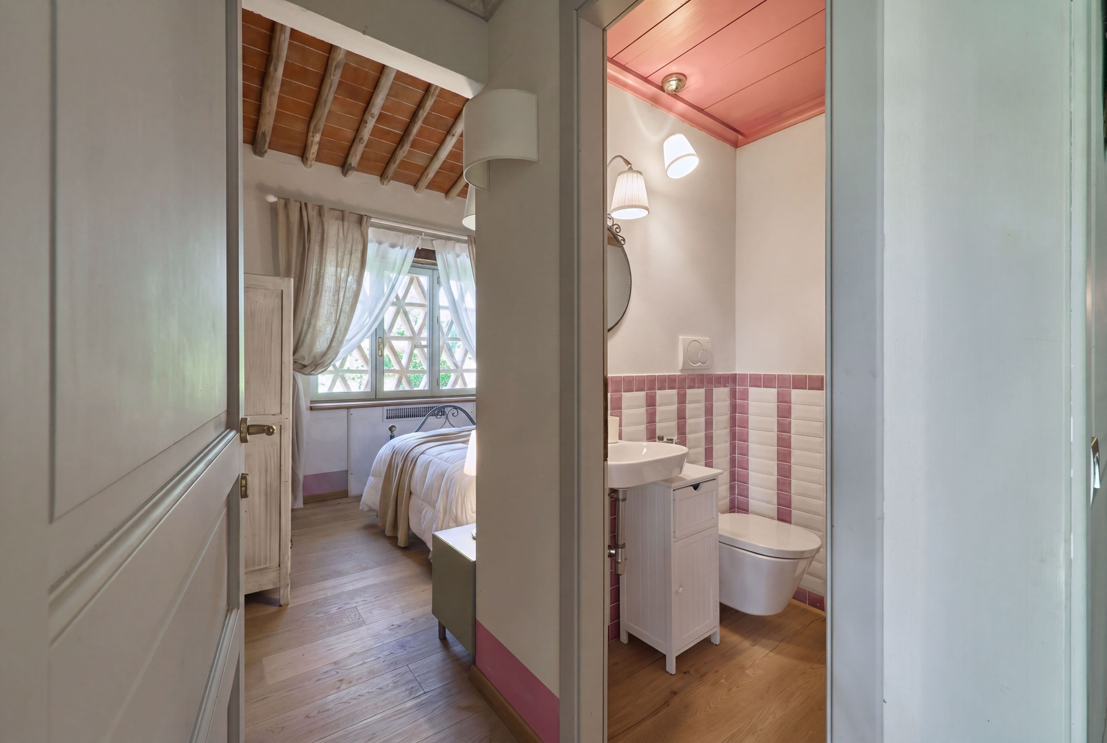 Ein Schlafzimmer mit Bett, einem fensterbepflanzten Fenster, einer Holzzahl und einem Badezimmer mit Waschbecken und Toilette.