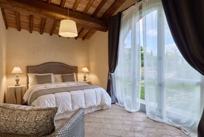 A bedroom with a bed, two bedside tables with lamps, a chair, and a large window with curtains. - Villa Noce by My Villa Collection (Barberino Tavarnelle)