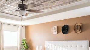 A bedroom with a tufted headboard, a large bed with a patterned bedspread, a floor lamp, and a ceiling fan. - Giddyup Getaway: Western Oasis w/ Pool! 4bd 9 beds (Cypress)