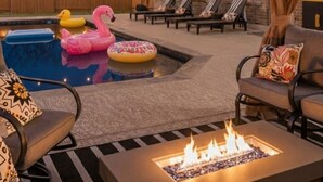 A covered outdoor area with a pool, lounge chairs, and a fire feature. - Giddyup Getaway: Western Oasis w/ Pool! 4bd 9 beds (Cypress)