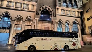 Ein Bus ist vor einem Gebäude mit Rundbogenfenstern und einem Schild mit der Aufschrift "SNOOD" geparkt.