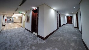 Ein Hotelgang mit Teppichböden, Türen und Notausgangsschildern.