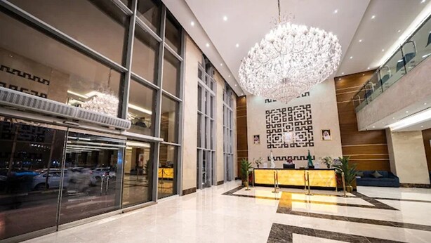Eine moderne Lobby mit einem großen Kronleuchter, Glastüren und einer Rezeption.