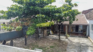 Um pátio com uma grande árvore, uma área cercada e um edifício com telhado de azulejos.