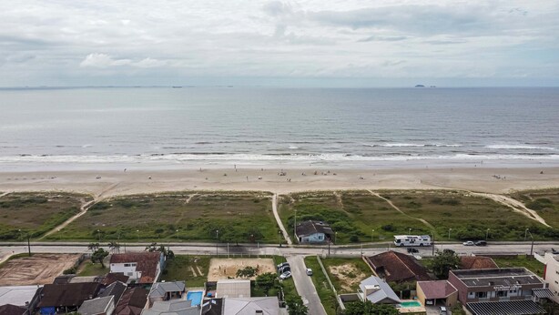 Uma praia com uma estrada que leva a um prédio com piscina.