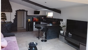 Een moderne keuken met een stenen keukeneiland, zwarte barkrukken en een grote flatscreen-televisie.