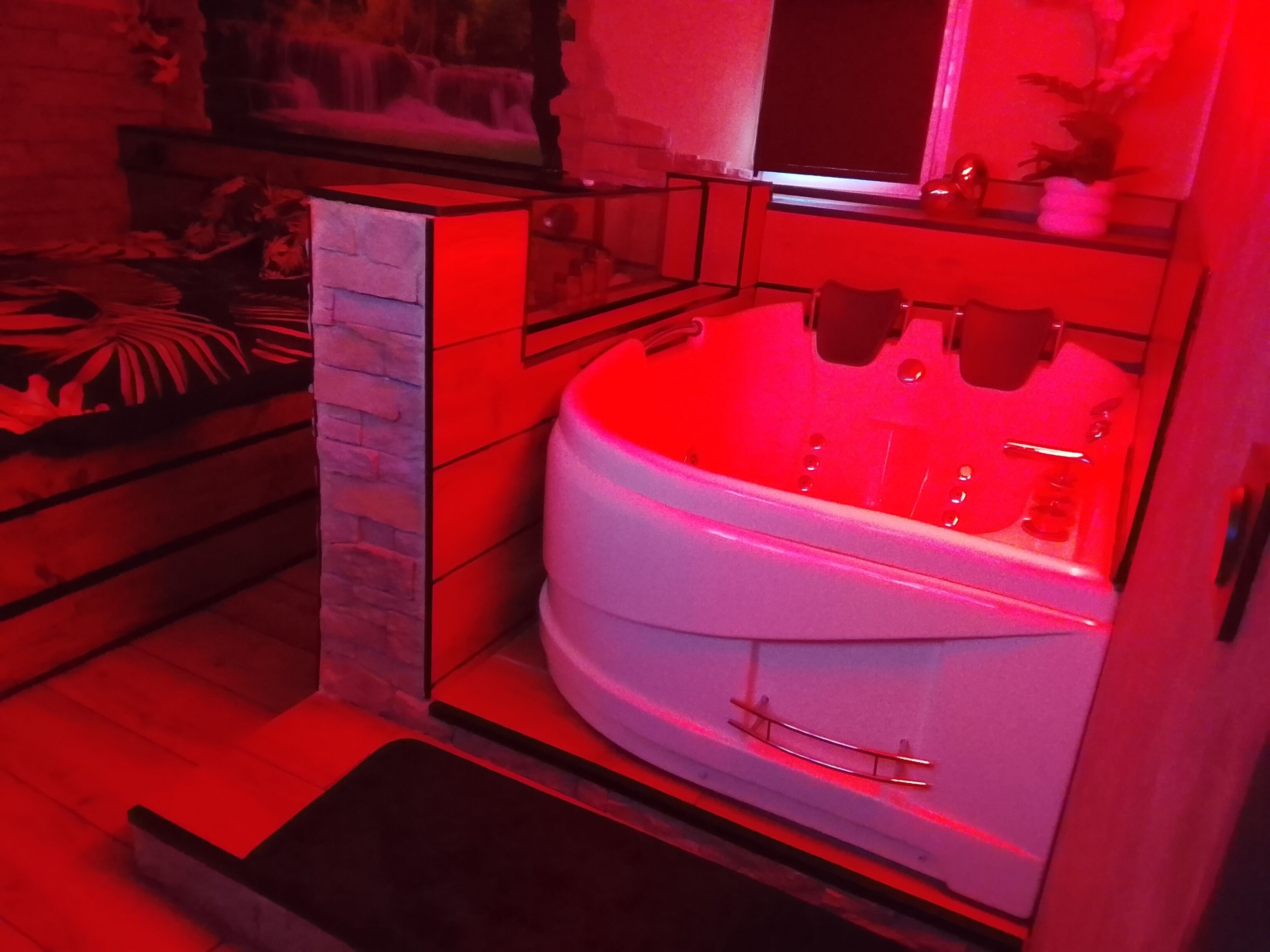 A modern bathroom with a large bathtub, a glass shower enclosure, and a stone accent wall.