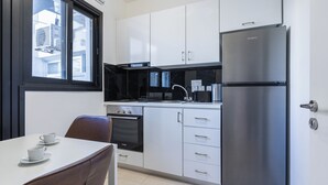 Een moderne keuken met witte kasten, een roestvrijstalen koelkast en een eethoek met een tafel en stoelen.