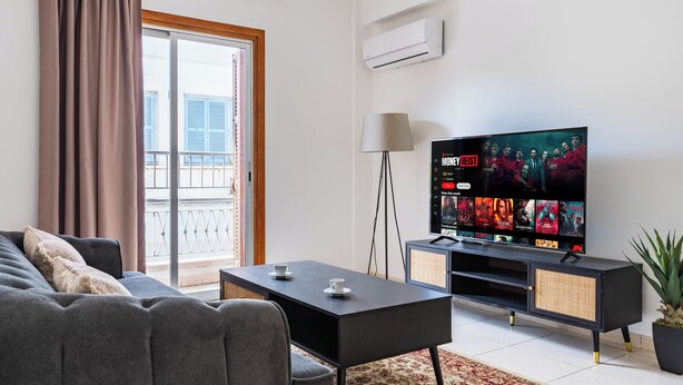 Een moderne woonkamer met een bank, een salontafel, een televisie en een balkon met uitzicht.