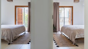 Een spiegelbeeld van een slaapkamer met een bed, een raam met houten luiken, een balkon en een hanglamp.