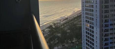 A high-rise building with a view of the ocean at sunset.