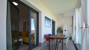 A dining area with a table and chairs, a sofa, and a painting on the wall.