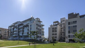 A modern apartment complex with multiple floors, balconies, and a well-maintained lawn area.