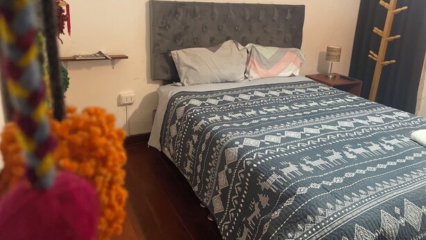 Ein Hotelzimmer mit Bett, Nachttisch, Lampe und Garderobe.