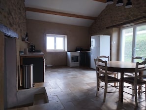 Eine Küche mit Fenster, Kühlschrank, Herd und einem Esstisch mit Stühlen.