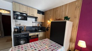 Een kleine keuken met een wasmachine, een magnetron en een koelkast.