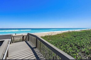 A wooden boardwalk leading to a beach with clear blue water and a distant shoreline. - Right on the Water ! Wonderfull 1/1 condo (Stuart)