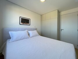 Quarto com cama, guarda-roupa e um quadro na parede.